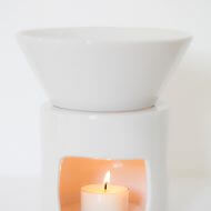 Large white ceramic oil burner with lit tealight candle inside